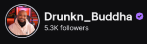Drunkn_Buddha's Twitch logo and follower count (5.3k). Logo is of a smiling bald black man wearing a white hoodie. Image links to Drunkn_Buddha's Twitch page.
