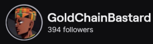 GoldChainBastard's Twitch logo and follower count (394). Logo is a cartoon style picture of a bald black man wearing a Kente cloth patterned kufi hat. Image links to GoldChainBastard's Twitch page.