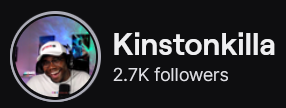 KinstonKilla's Twitch logo and follower count (2.7k). Logo is a picture of a black man wearing a white shirt and baseball cap, smling while talking into a mic. Image links to KinstonKilla's Twitch page.
