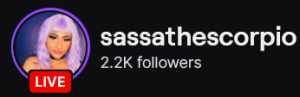 SassaTheScorpio's Twitch logo and follower count (2.2k). Logo is a picture of a black person (femme presenting) with lavender hair. Image links to SassaTheScorpio's Twitch page.