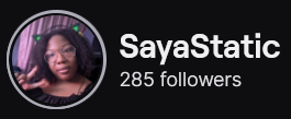 SayaStatic's Twitch logo and follower count (285). Logo is a picture of a black woman with collarbone length hair making the peace sign while wearing cat ear headphones. Image links to SayaStatic's Twitch page.
