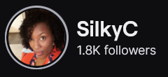 SilkyC's Twitch logo and follower count (1.8k). Logo is a picture of a black woman with a curly afro wearing a red shirt. Image links to SilkyC's Twitch page.

